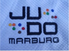 Das Bild zeigt das Logo des Judo-Dojo Marburg. Der Schriftzug „JU DO MARBURG“ ist klar und deutlich. Farbig gestaltete Punkte sind um den Text verteilt, die dem Logo einen lebendigen Akzent verleihen.